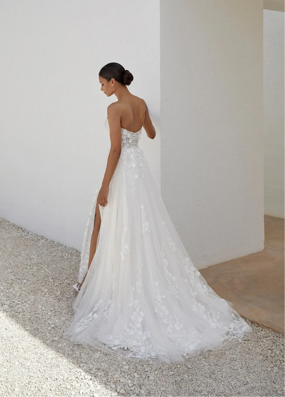 Woman in a white wedding dress standing in a minimalistic indoor setting.
