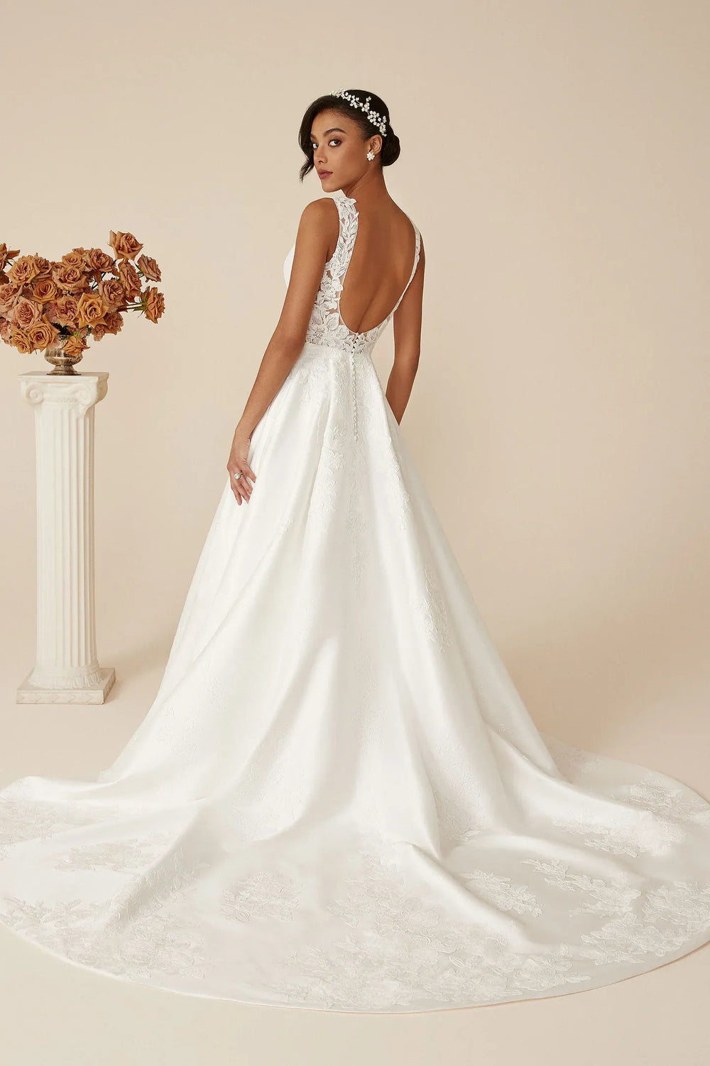 Woman in a white wedding dress with a floral arrangement on a beige background