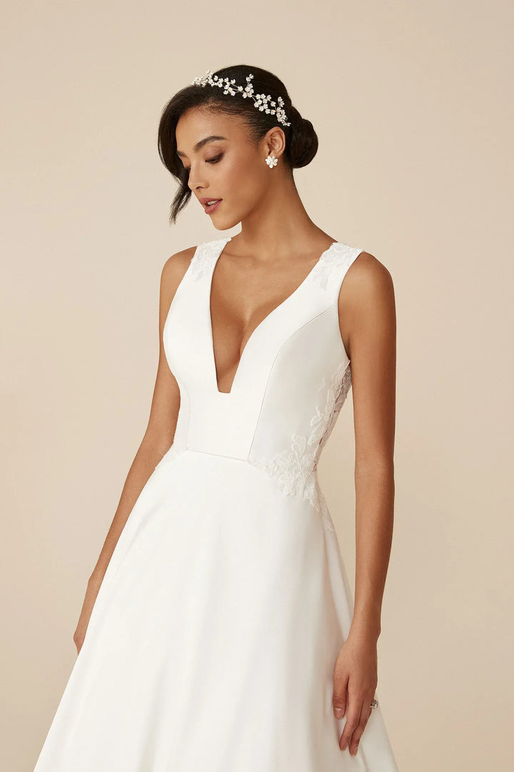 Woman wearing a white wedding dress with a deep neckline on a beige background