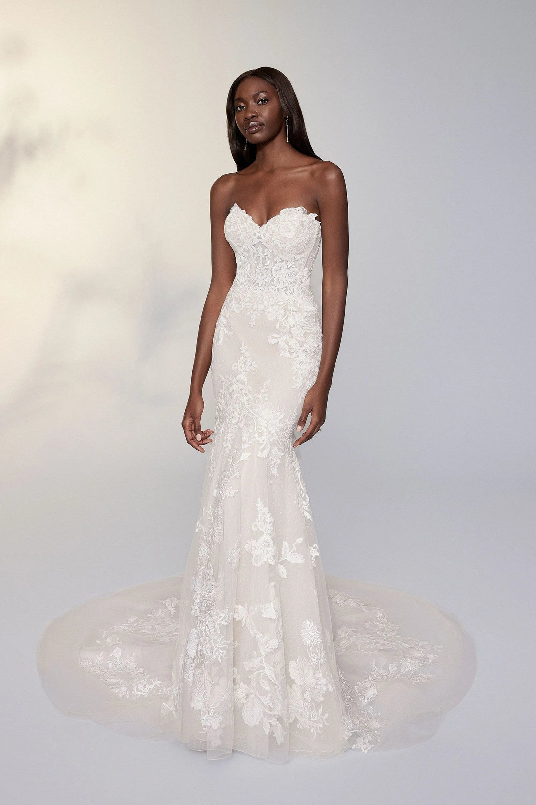 Woman wearing a strapless lace wedding dress on a white background