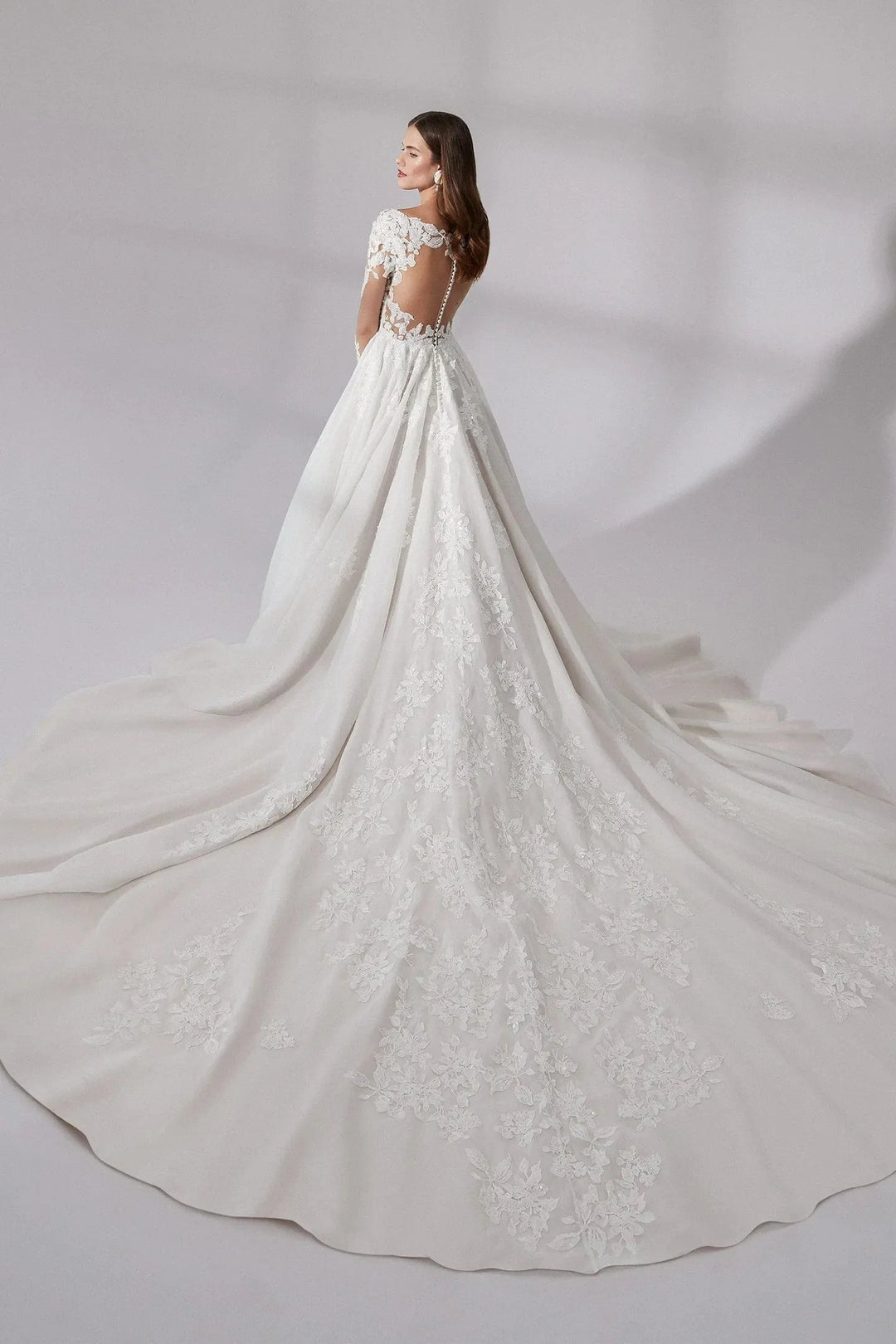 Elegant white wedding dress with lace details on a plain background