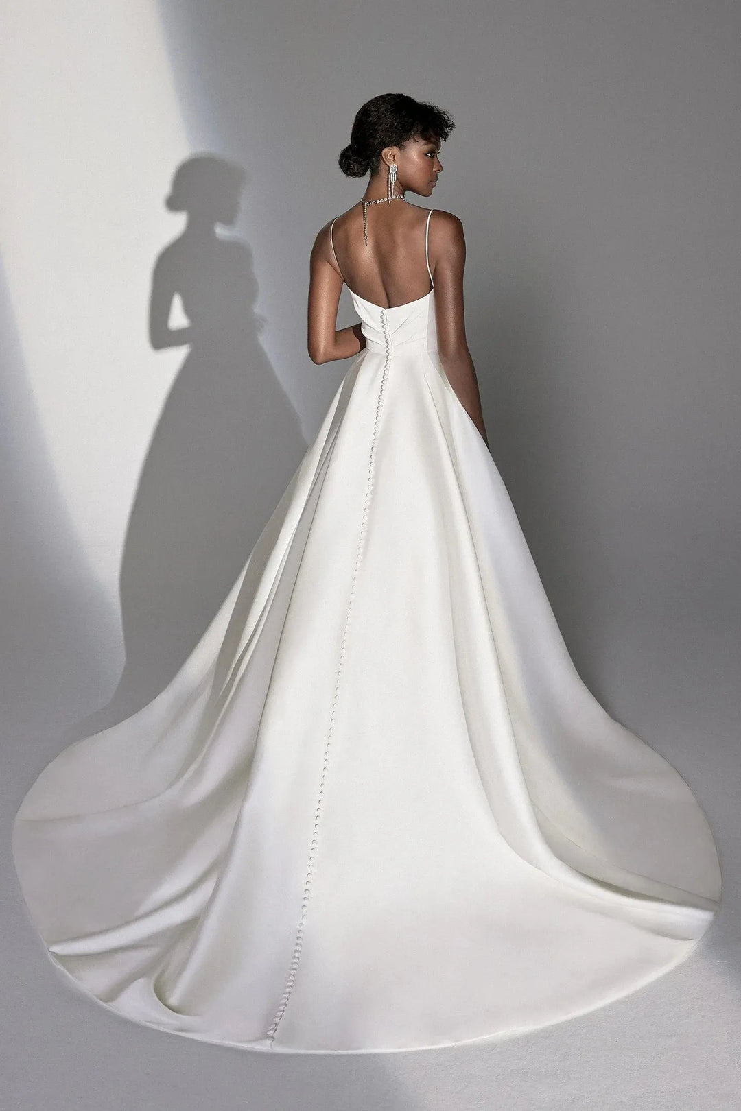 White wedding dress with a long train on a plain background