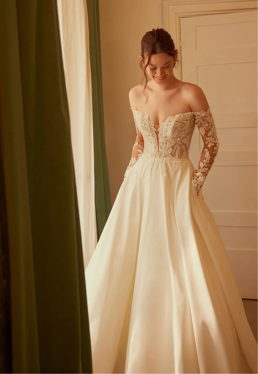 Woman in a white wedding dress with lace bodice standing in a room.