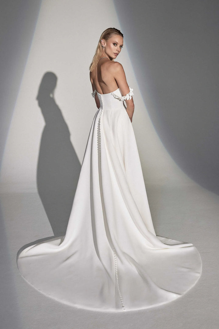 Woman in a white wedding dress with a long train on a gray background