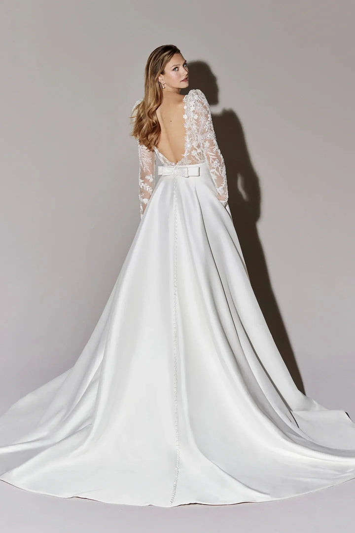 White wedding dress with lace sleeves on a plain background