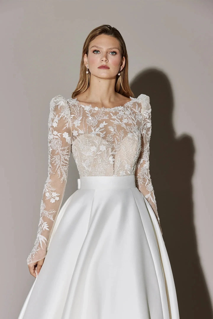 Model wearing a wedding dress with lace top and white skirt against a neutral background