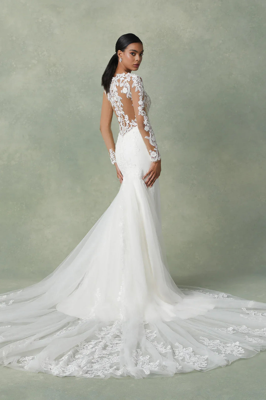 Woman wearing a white wedding dress with floral details on a plain background