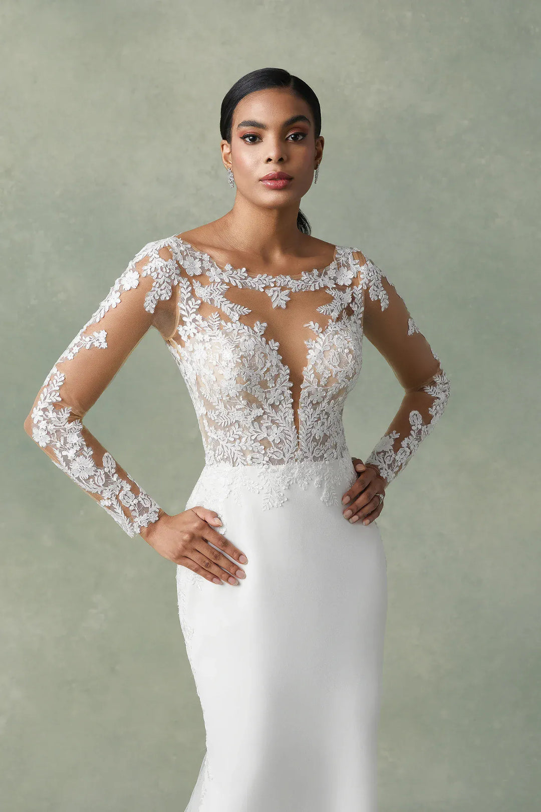 Woman wearing a white wedding dress with lace sleeves against a neutral background