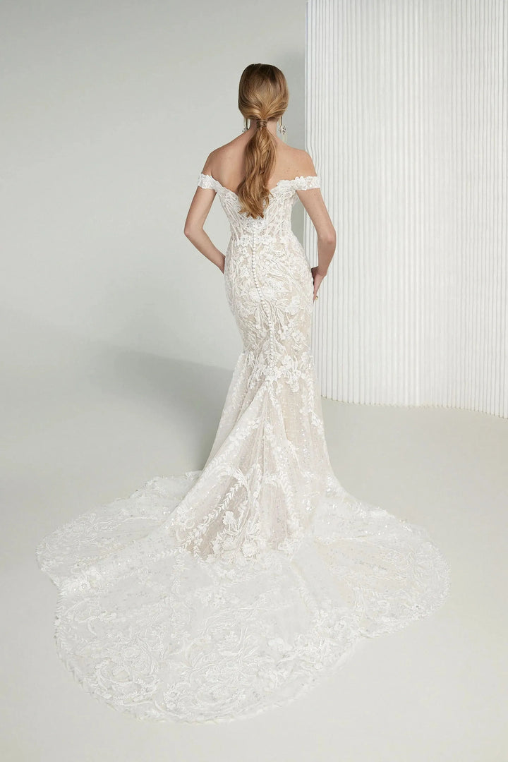 Woman wearing a white lace wedding dress against a plain background