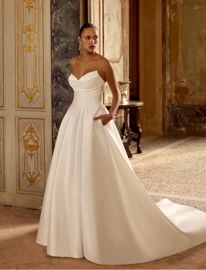 Woman in a white wedding dress standing in an ornate room.