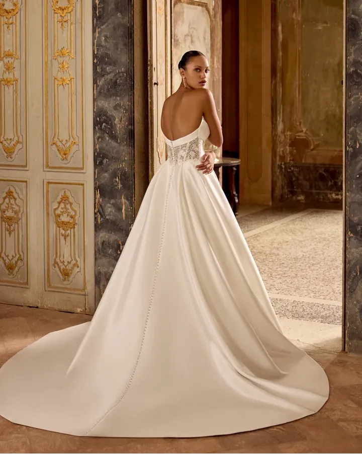 Woman in a white wedding dress standing in an ornate room with decorative walls.