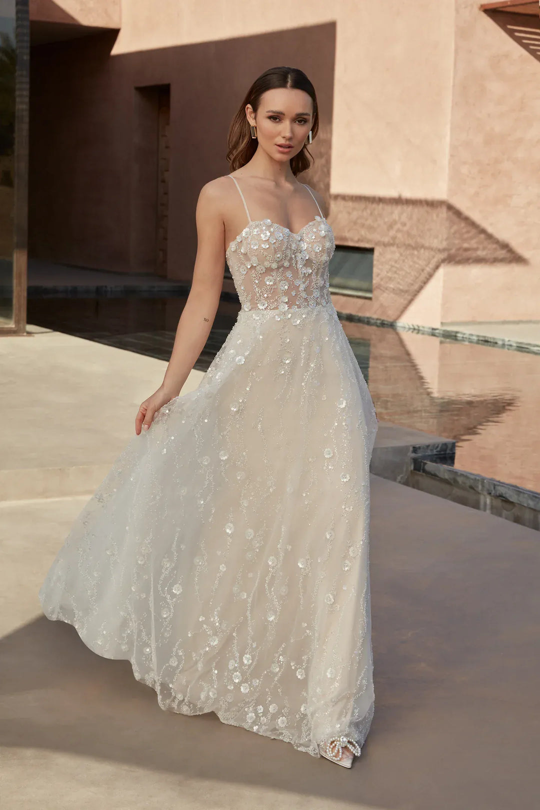 Woman in a white floral dress standing in front of a modern architectural background