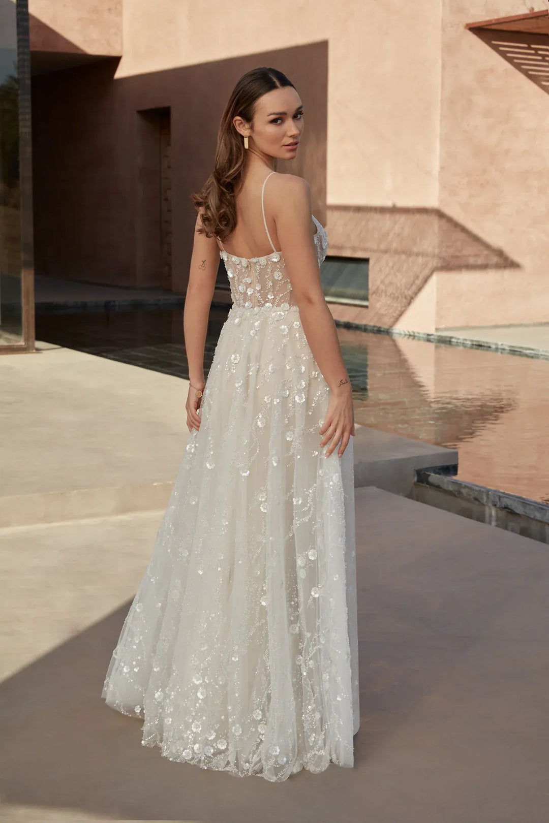 Woman in a white lace dress standing in front of a modern architectural background