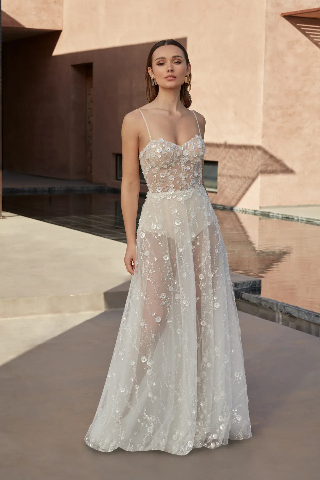 Woman wearing a white floral dress standing in front of a modern architectural building.