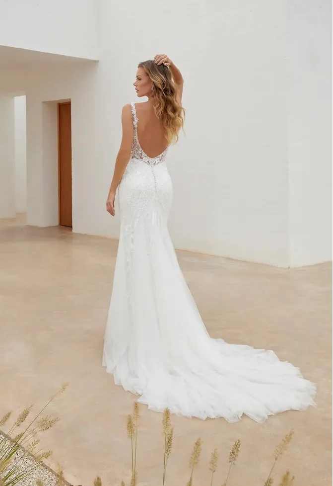 Woman in a white wedding dress standing in a minimalist outdoor setting.