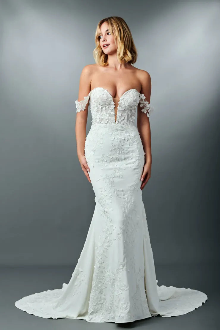 Woman wearing a white lace wedding dress against a gray background