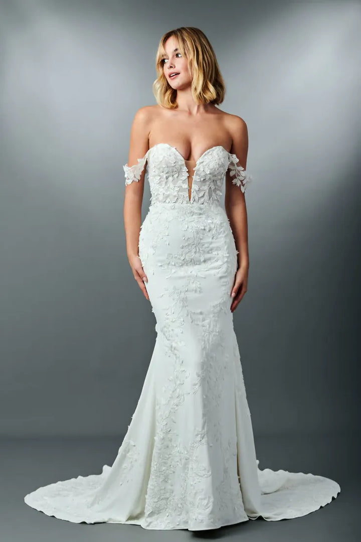 Woman wearing a white lace wedding dress against a gray background