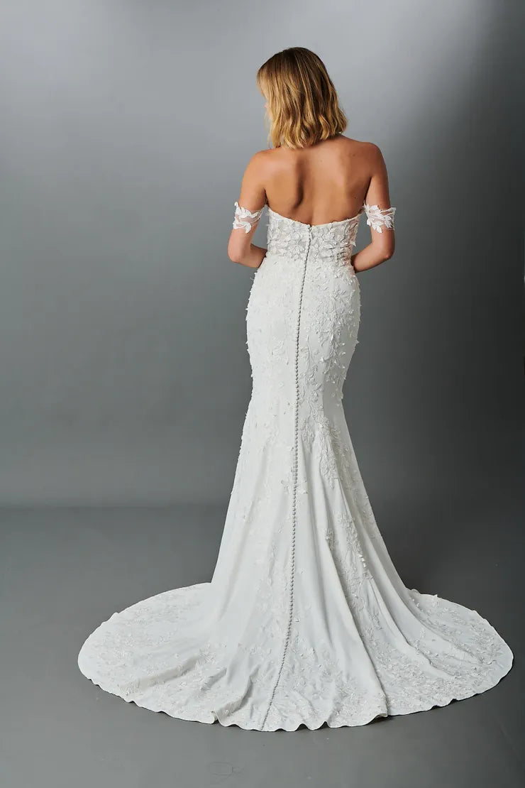 Woman wearing a white lace wedding dress with a gray background