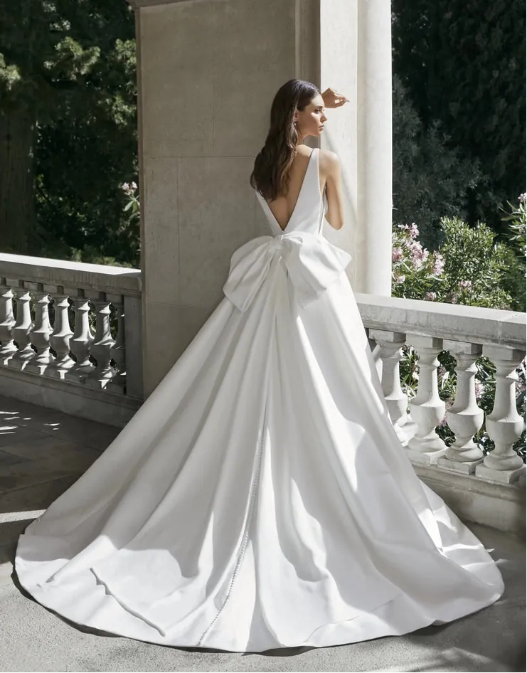 Woman in a white wedding dress standing on a stone pathway with greenery in the background