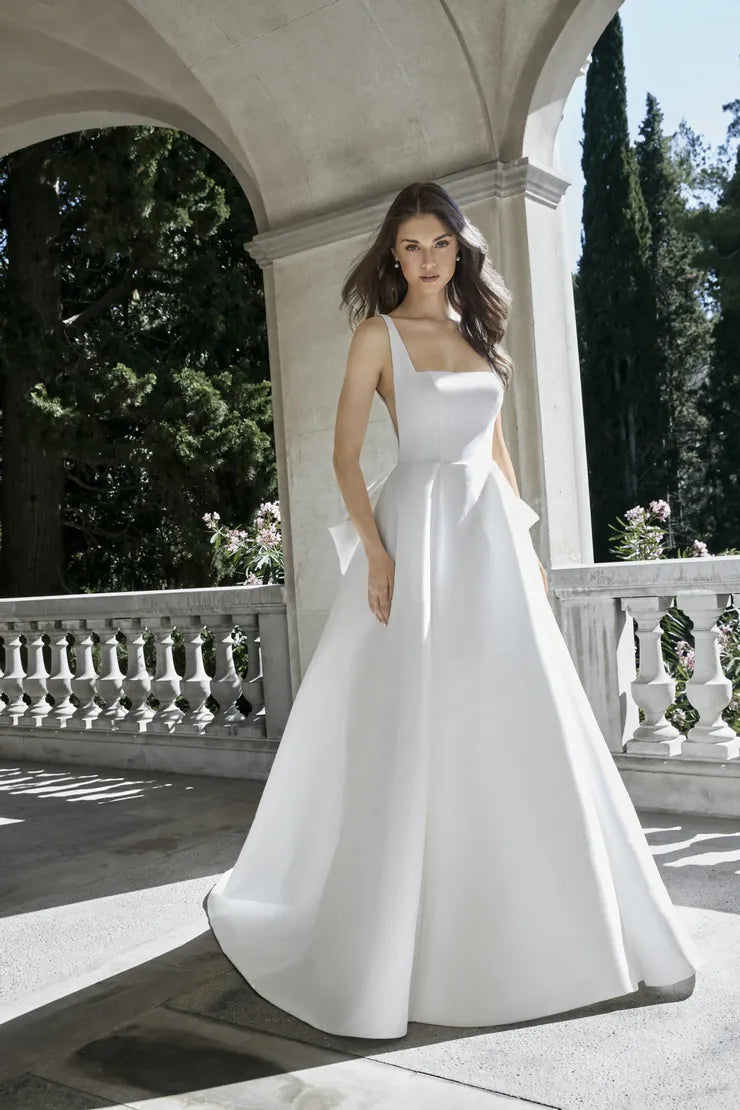 Woman in a white wedding dress standing on a stone path with greenery in the background