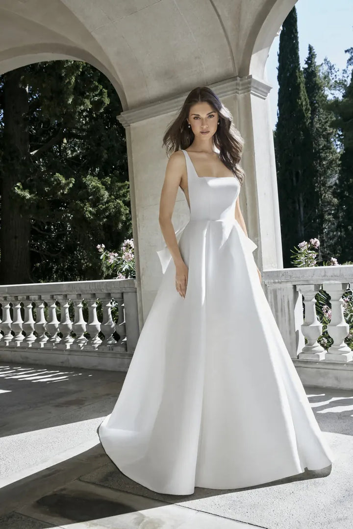 Woman in a white wedding dress standing on a stone path with greenery in the background