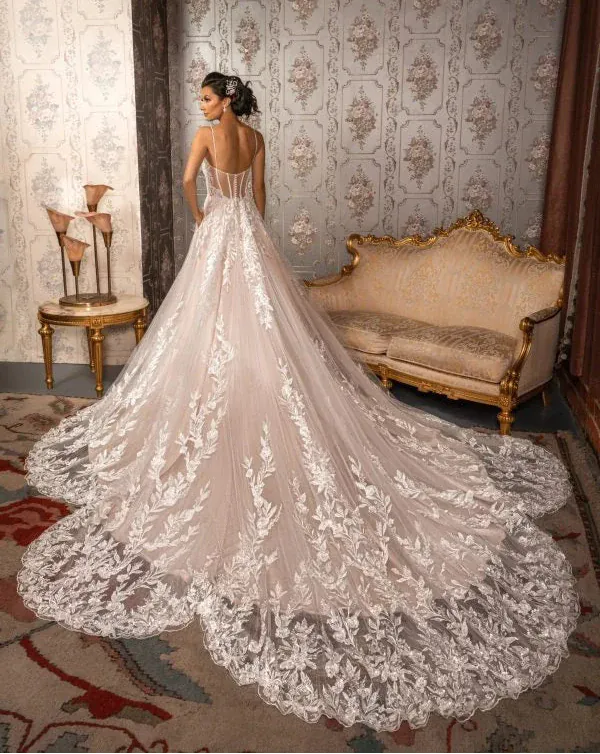 Woman in a lace wedding dress standing in an ornate room with floral wallpaper.