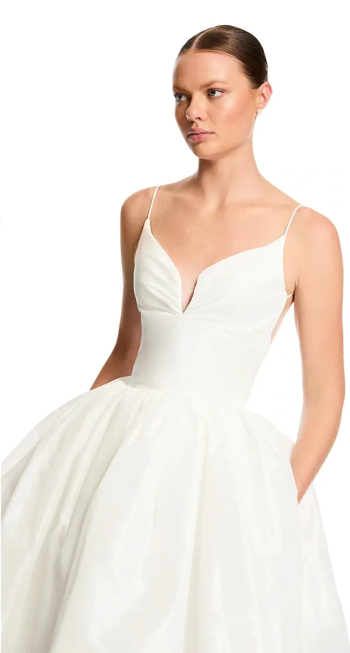 White wedding dress with thin straps worn by a model on a white background