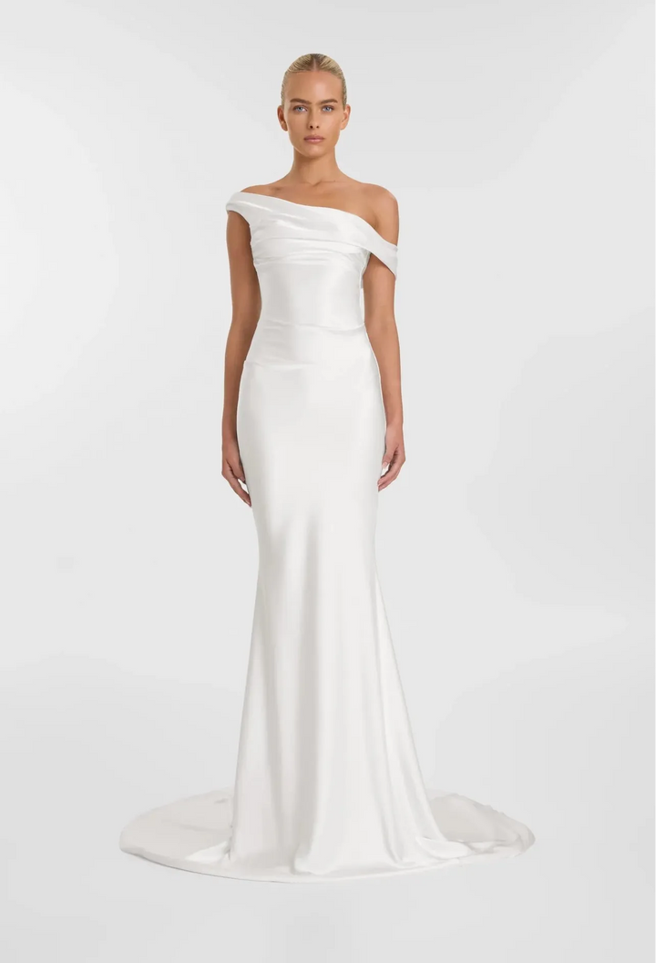 Woman wearing a white off-shoulder gown on a plain background