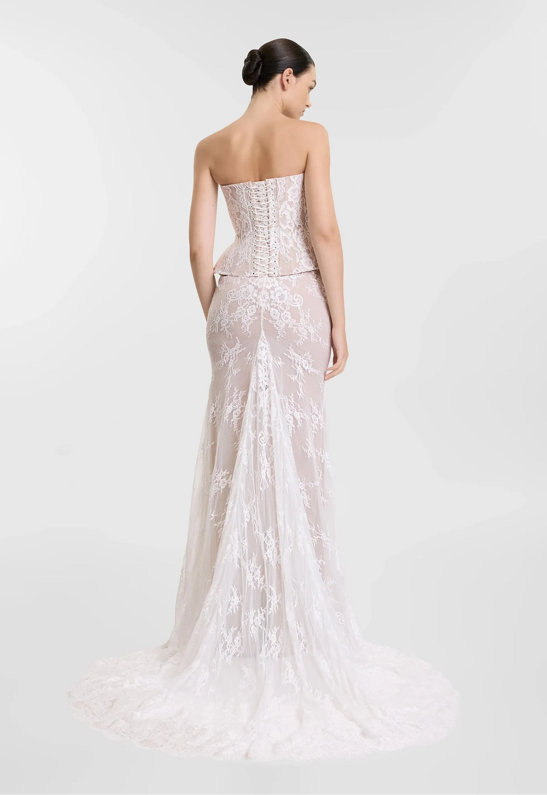 Woman wearing a strapless, embroidered evening gown on a white background