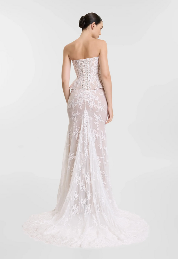 Woman wearing a strapless, embroidered evening gown on a white background