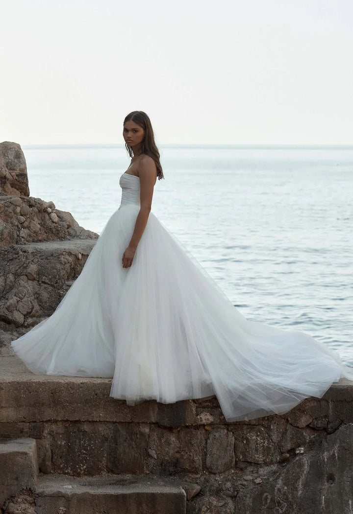 full side of kyha malibu ivory tulle ball gown wedding dress featuring a full airy skirt and train