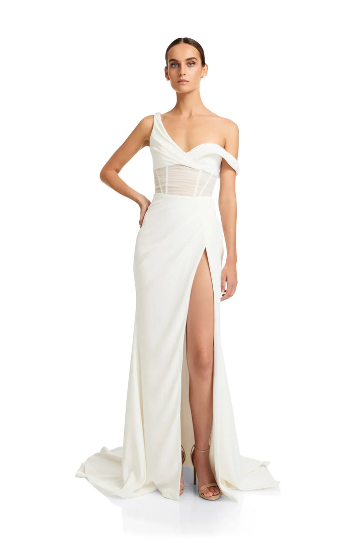 Woman wearing a white evening gown with a high slit on a white background