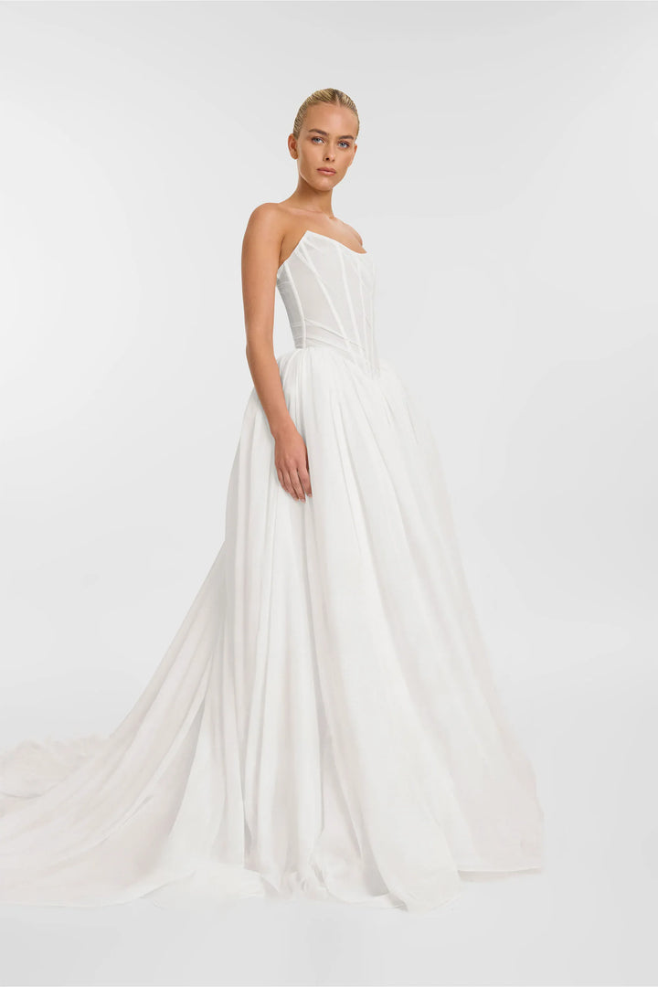 Woman wearing a white strapless gown on a plain background