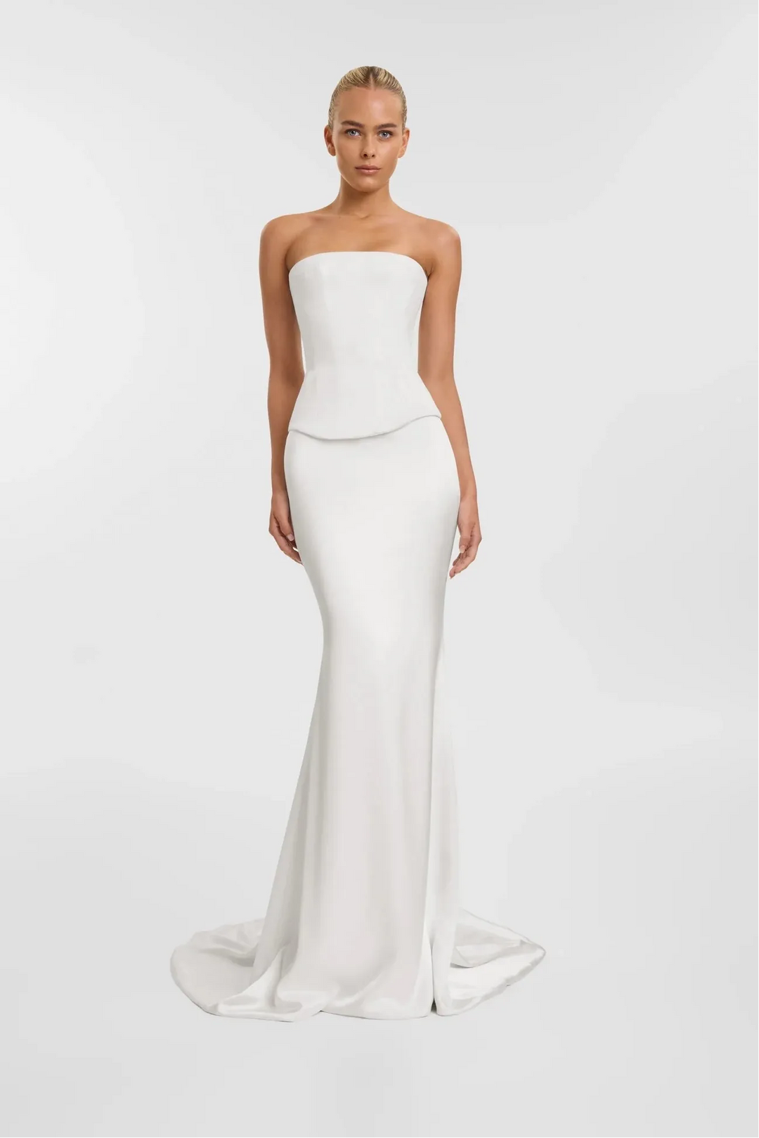 Woman wearing a strapless white gown on a plain background