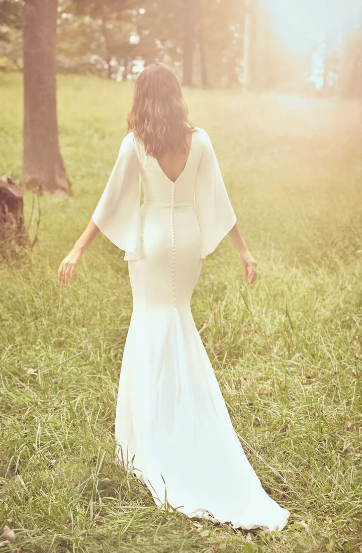 Woman in a white dress standing in a grassy field with a warm, sunlit glow.
