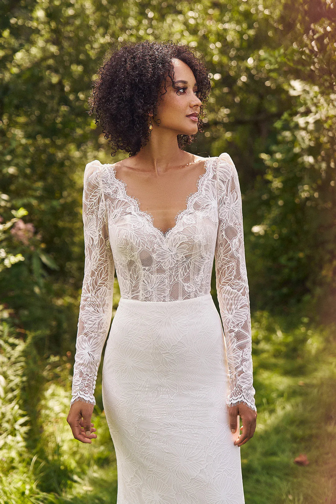 Woman wearing a white lace wedding dress in a forest setting