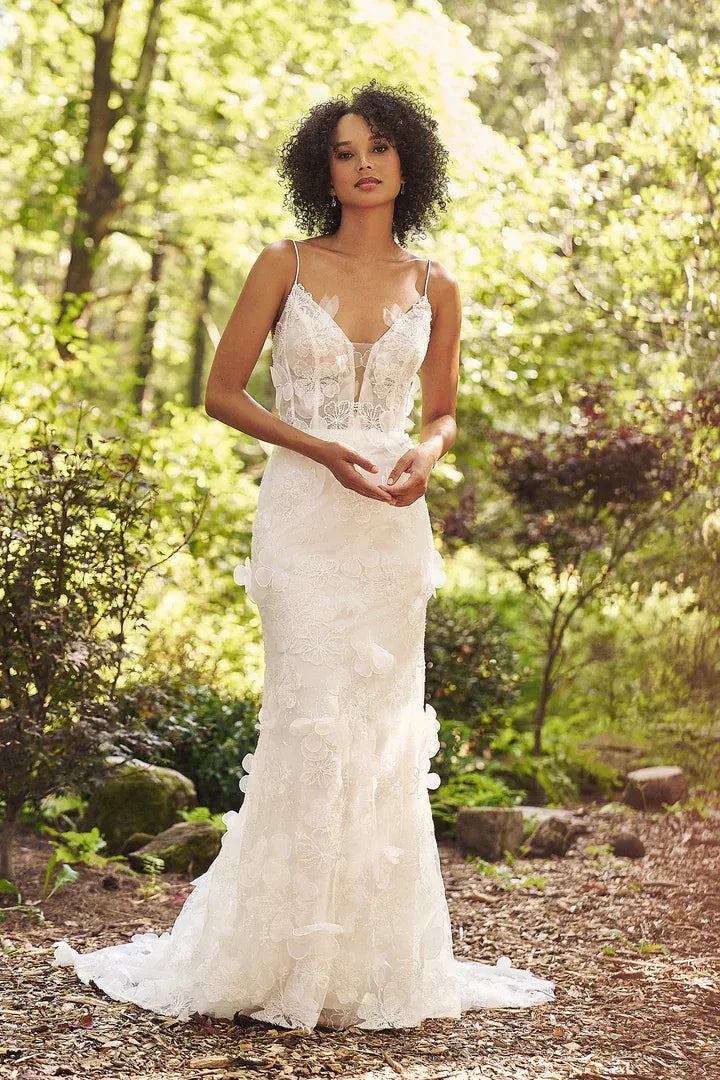 Woman in a white lace wedding dress standing in a forest