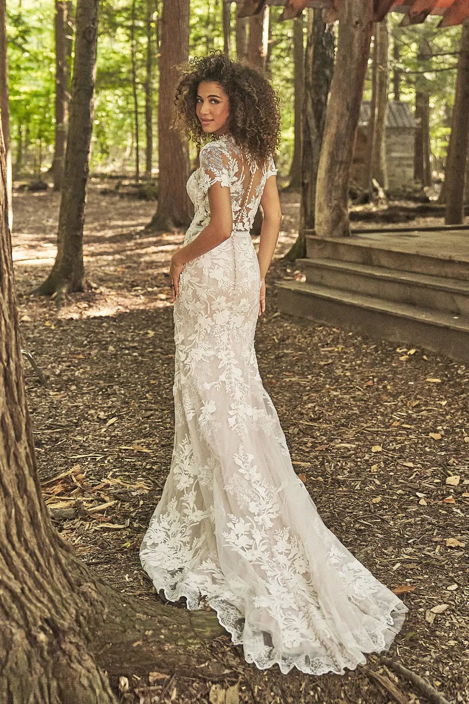 Woman in a white lace wedding dress standing in a forest