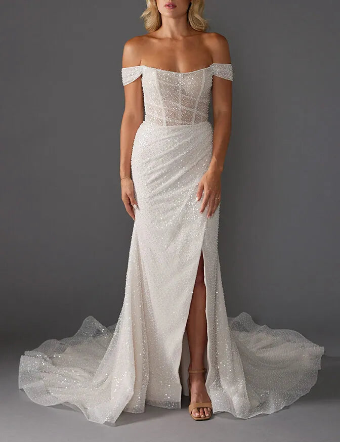 White off-shoulder beaded wedding dress with a slit on a gray background