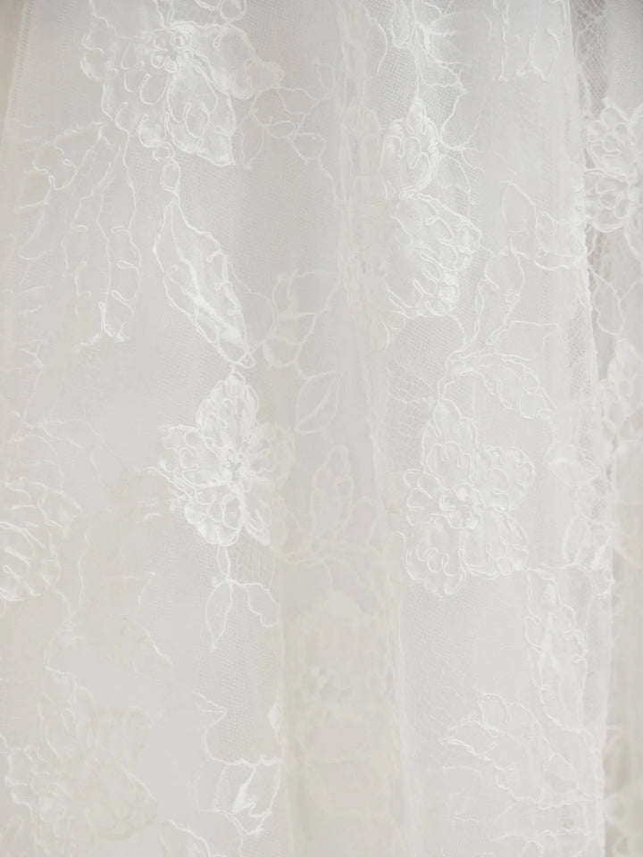 White floral lace fabric with delicate embroidered details and sheer tulle texture.