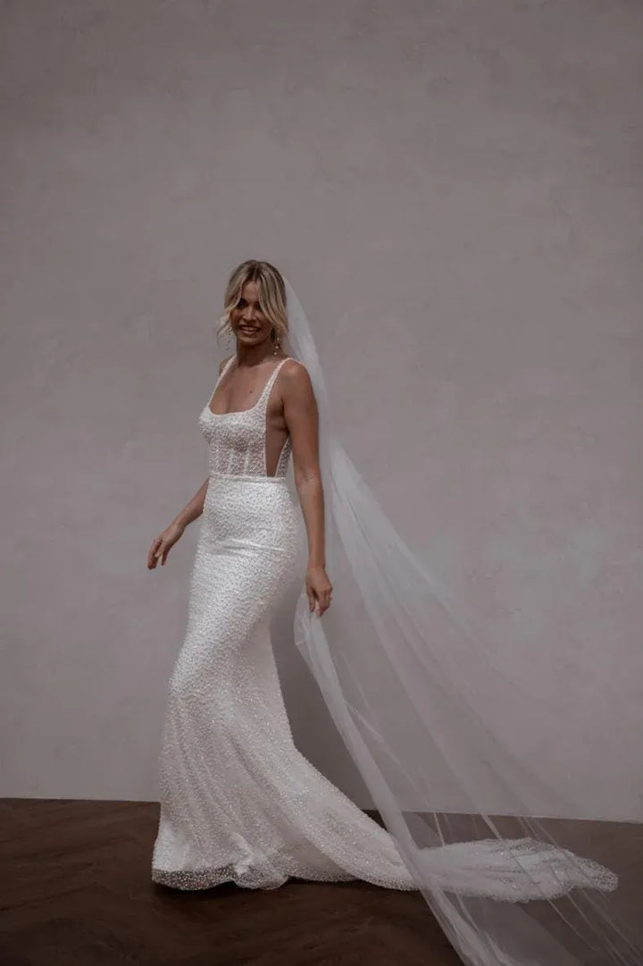 full front of made with love freddie ivory beaded fit and flare wedding dress with a square neckline and fitted skirt, with deep side cutouts