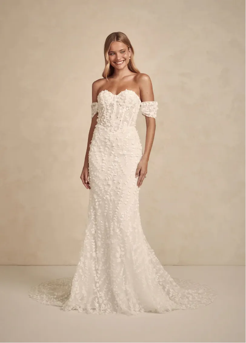Woman wearing a white lace wedding dress against a beige background