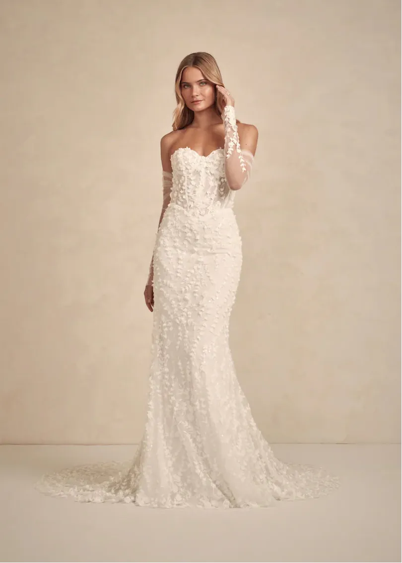 Woman wearing a white lace wedding dress against a beige background