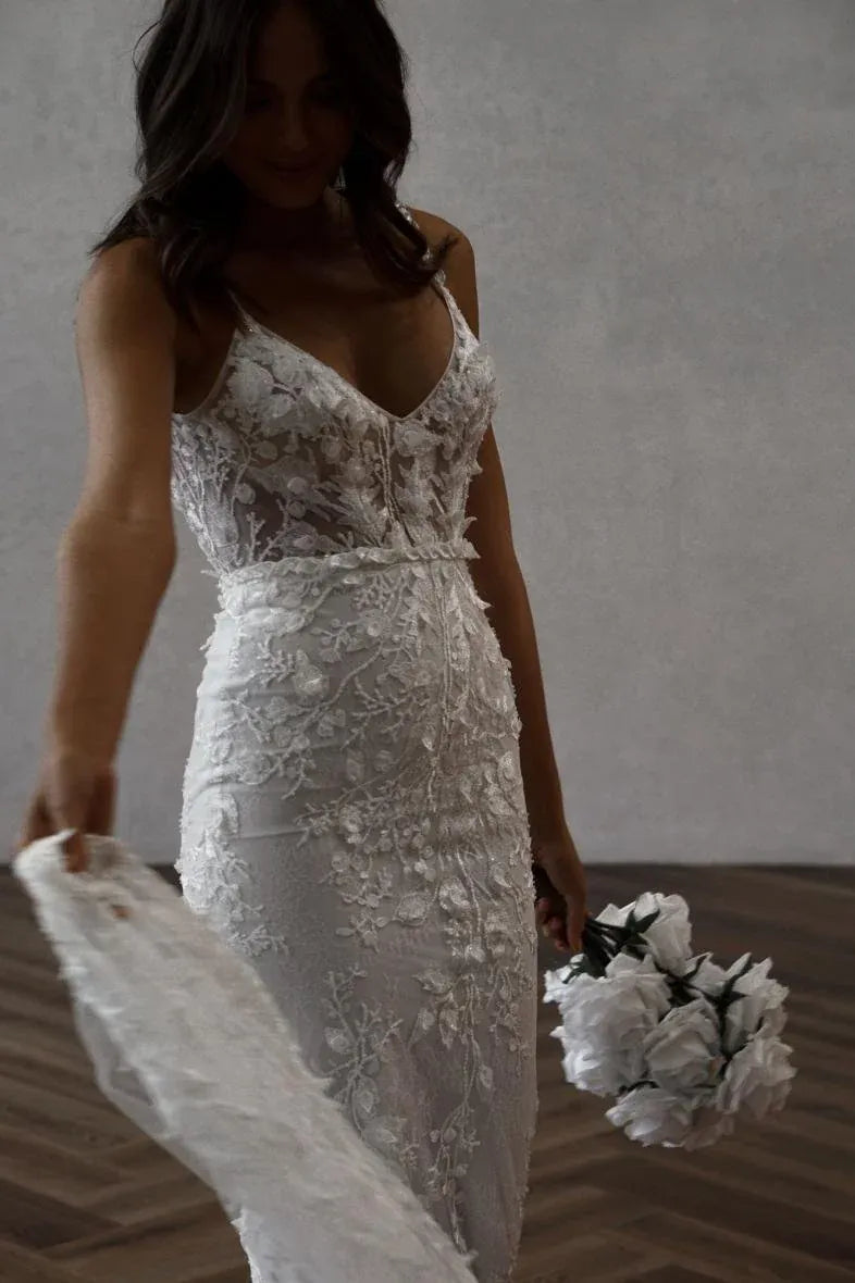 close up of made with love remi pebble colored lace fitted wedding dress with a v neckline and long train