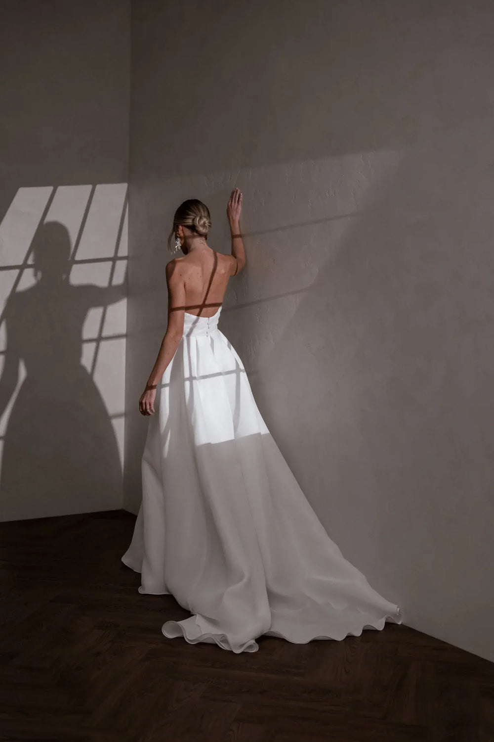 full back of made with love sloane ivory organza a-line wedding dress with a strapless bodice and flowy train at the back