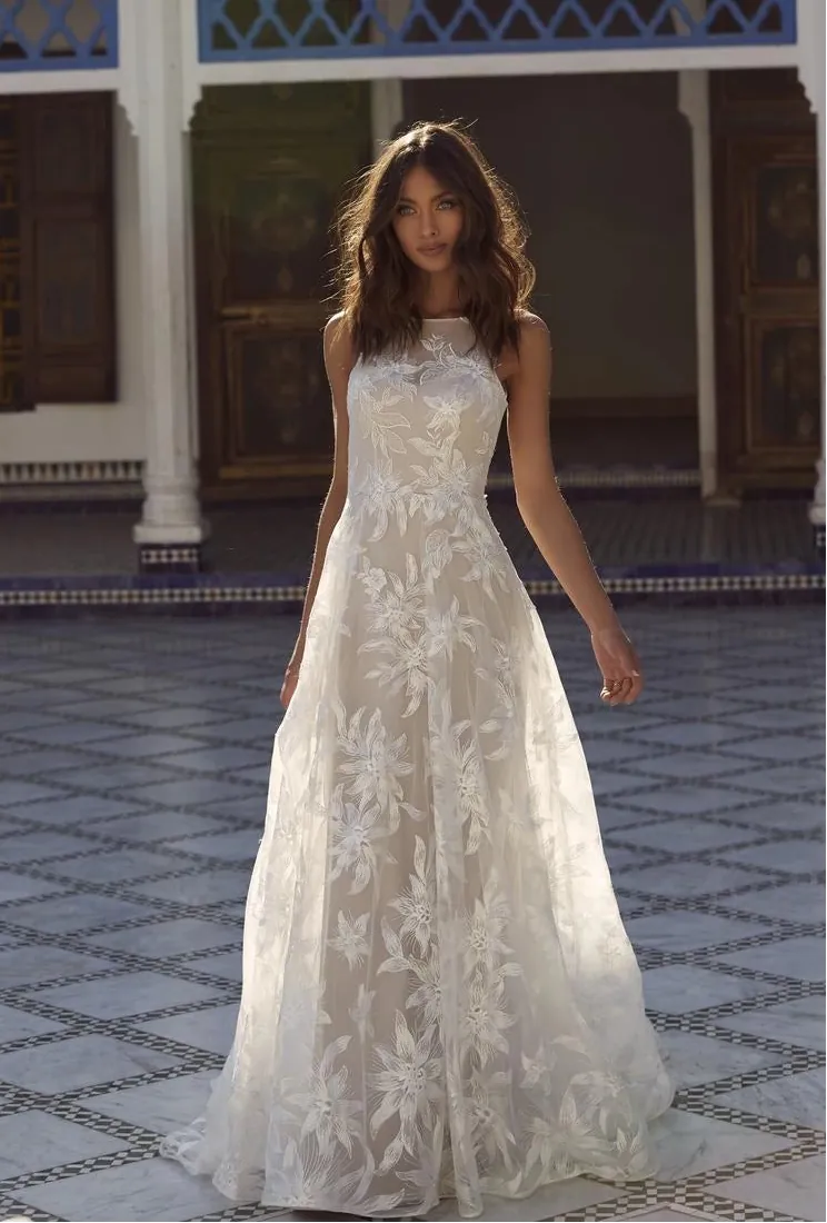Woman in a white lace dress standing in front of a traditional building with blue and white architecture.