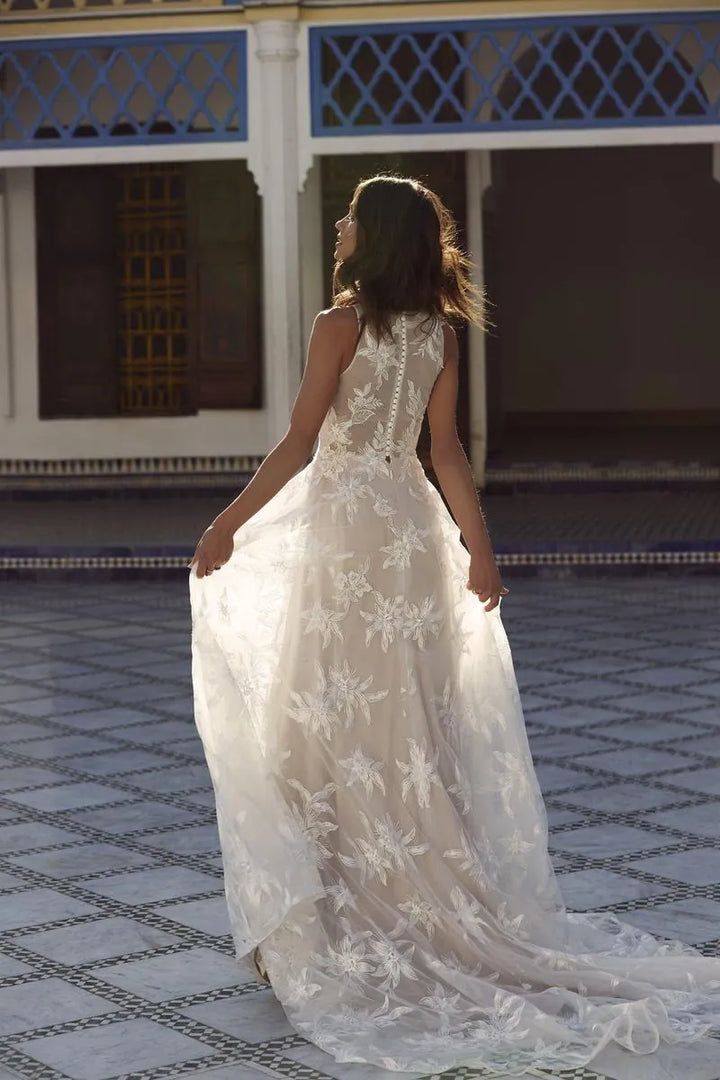 Woman in a white lace dress standing on a tiled floor with a decorative wall in the background