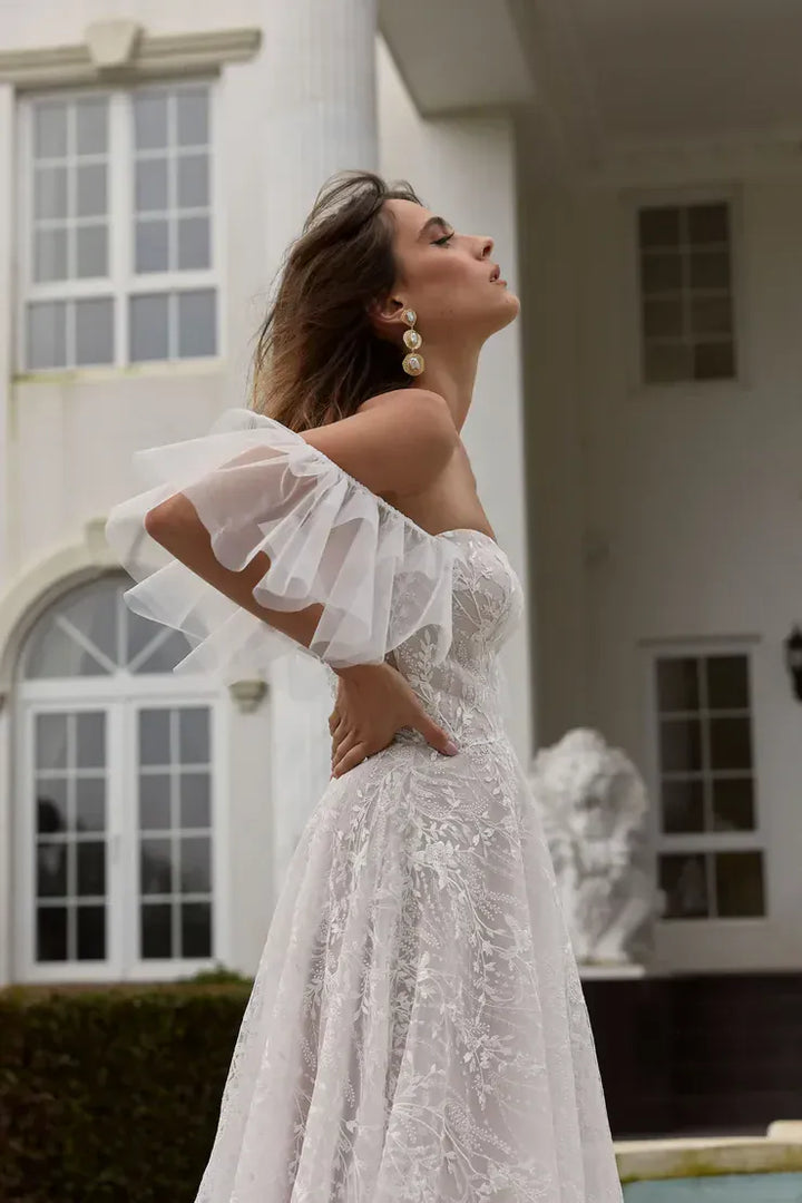 Woman in a white lace dress standing in front of a classical building.