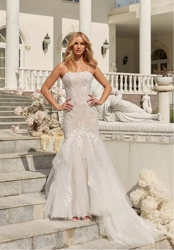 Woman in a white wedding dress standing on steps in front of a classical building.
