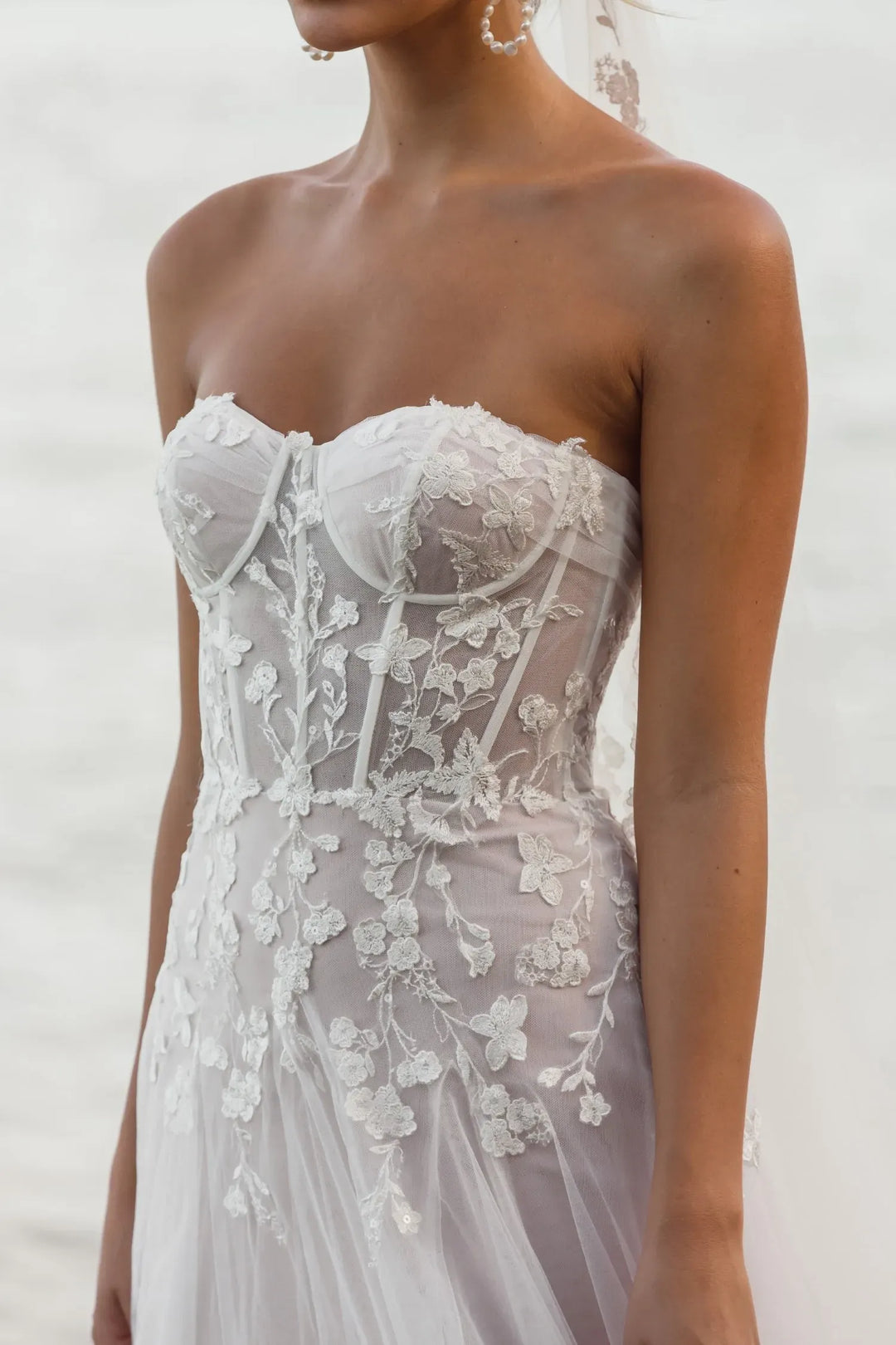 Lace wedding dress with floral details on a plain background